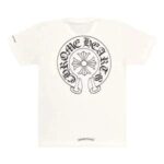 Chrome Hearts silver cross pendant resting on a heavyweight black streetwear hoodie with denim jeans in the background